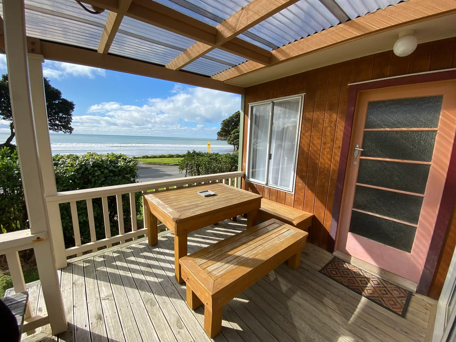 The covered timber deck at Bach A, with outdoor seating and a view of the sea