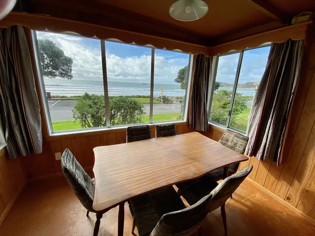 Dining table beside Bach A’s corner windows, looking across the road to Castlepoint beach