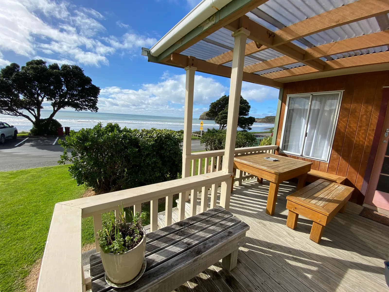 Bach A’s sunny timber deck, with a wooden table, outdoor chairs and the sea beyond