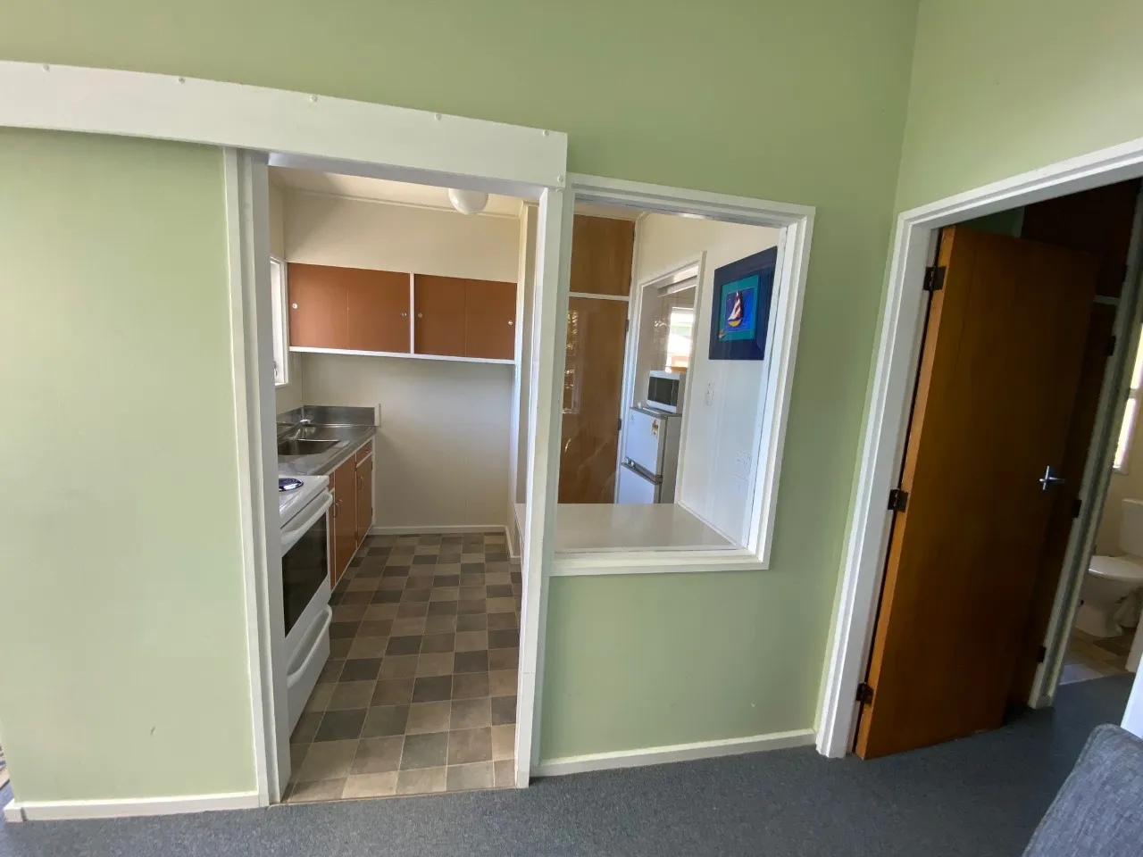 Kitchen serving hatch opening into Bach B’s living room